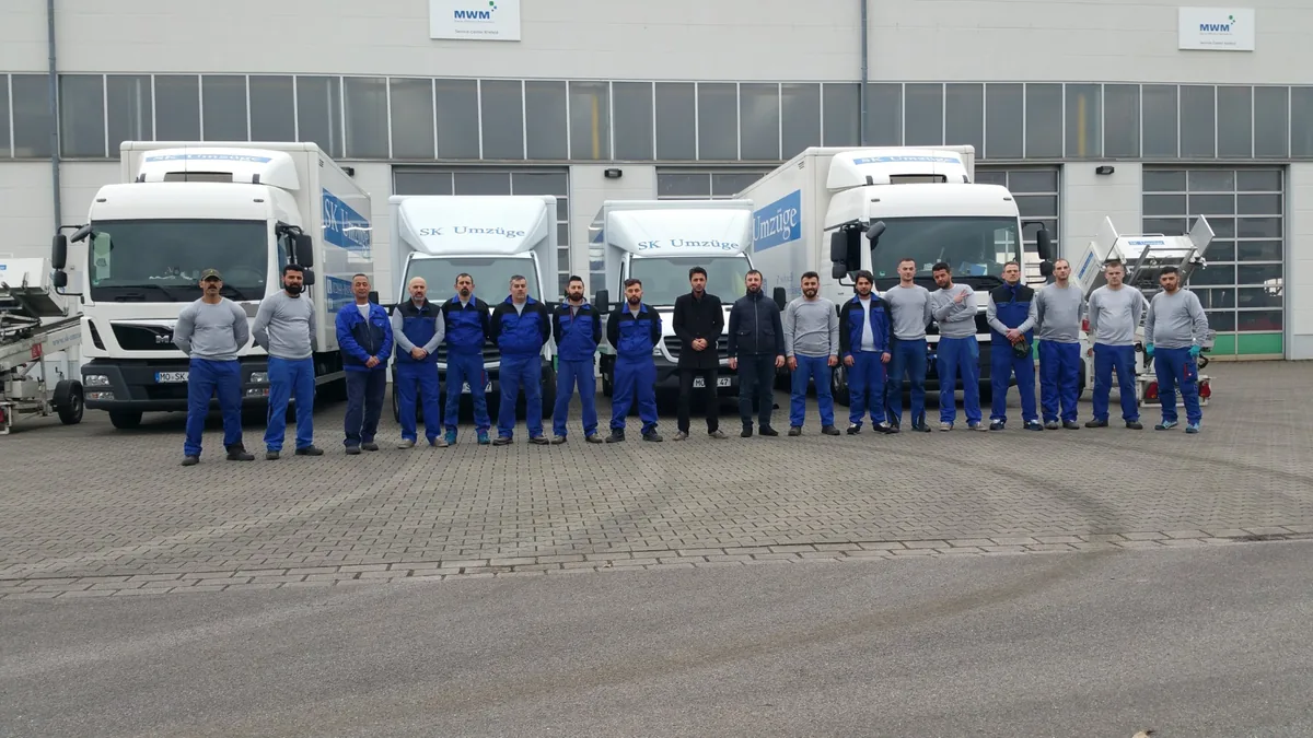 Team von SK-Umzüge vor Umzugswagen und Möbelliften